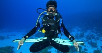 A diver sitting in a Buddha pose underwater